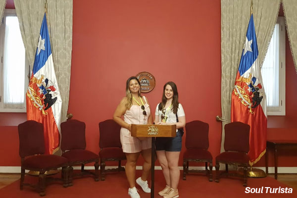 Eu e minha amiga numa famosa foto no palco usado para exibir comunicados oficiais na TV dentro do Palácio de La Moneda, sede do governo chileno, no Salão Montt-Varas