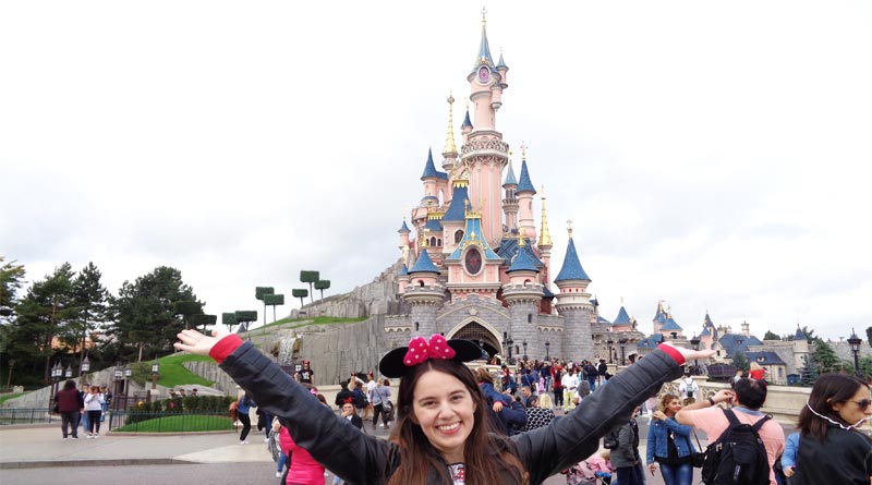 Eu em frente ao Castelo da Bela Adormecida toda feliz de braços abertos