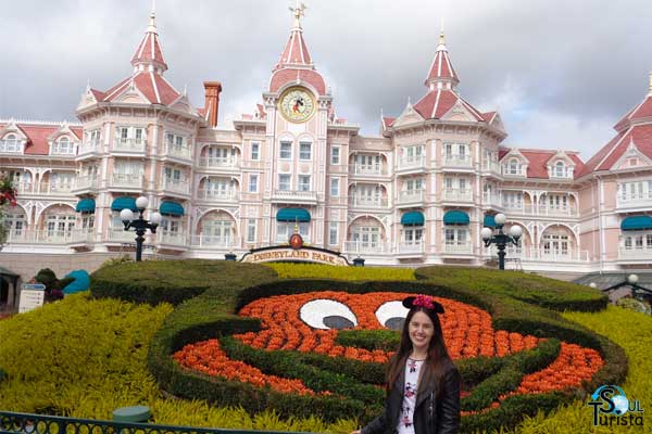 Minha foto em frente ao jardim na entrada do parque. Essa é uma das Disneyland Paris dicas de melhores fotos pois o jardim é com o formato do rosto do Mickey