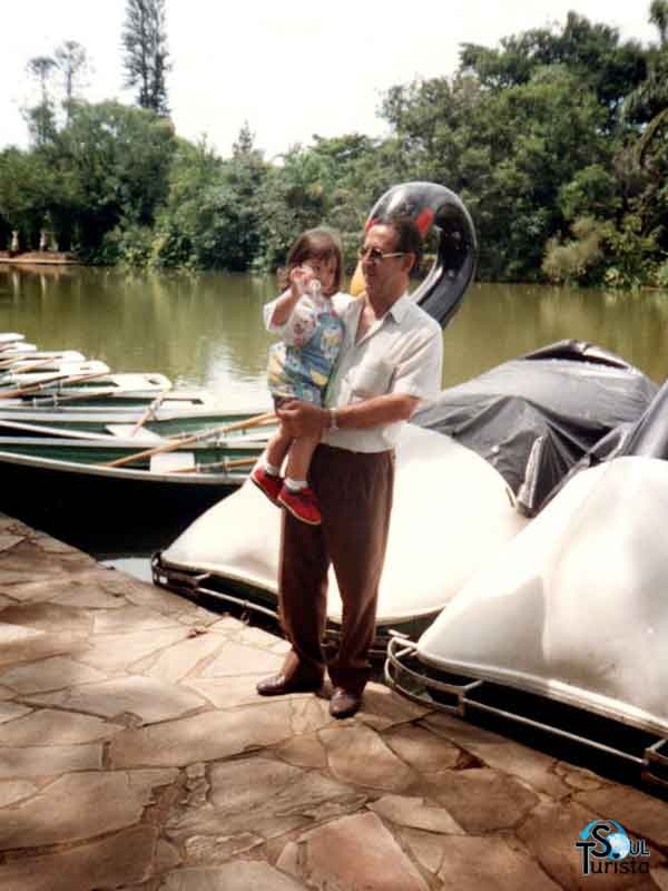 Eu criança no colo do meu avô em frente ao lago com pedalinhos do Parque das Águas São Lourenço