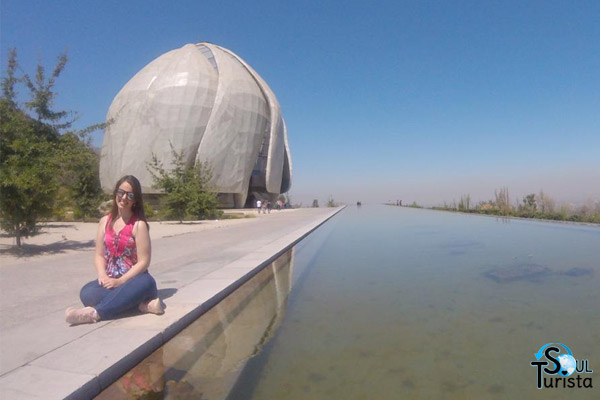 Minha foto sentada na borda do espelho d'água que fica às margens do Templo Bahai Chile