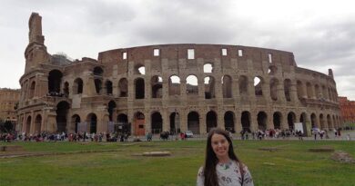 Eu em frente ao gramado e ao fundo está o Coliseu de Roma